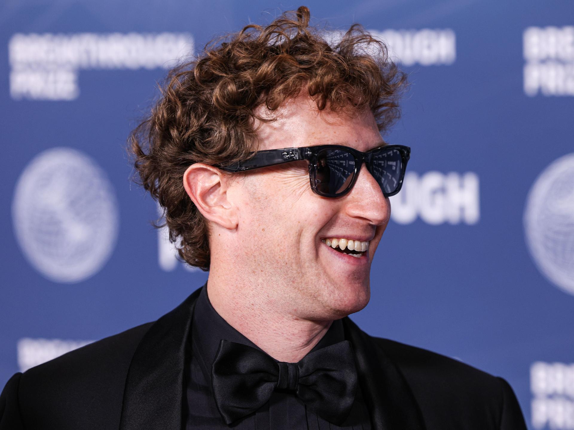 Der Meta-CEO Mark Zuckerberg trägt eine dunkel getönte Sonnenbrille, lächelt und schaut nach rechts.