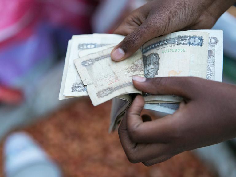 Marktszene in der Altstadt von Asmara in Eritrea: Hände zählen Geldscheine aus einem Bündel heraus. 