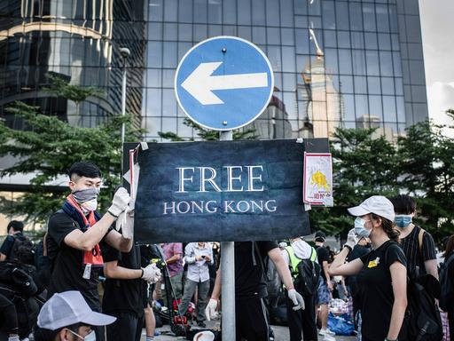 Protestierende befestigen am 01.07.2019 ein Plakat mit der Aufschrift "Free Hongkong" an einem Verkehrsschild vor dem Legislativrat in Hongkong.