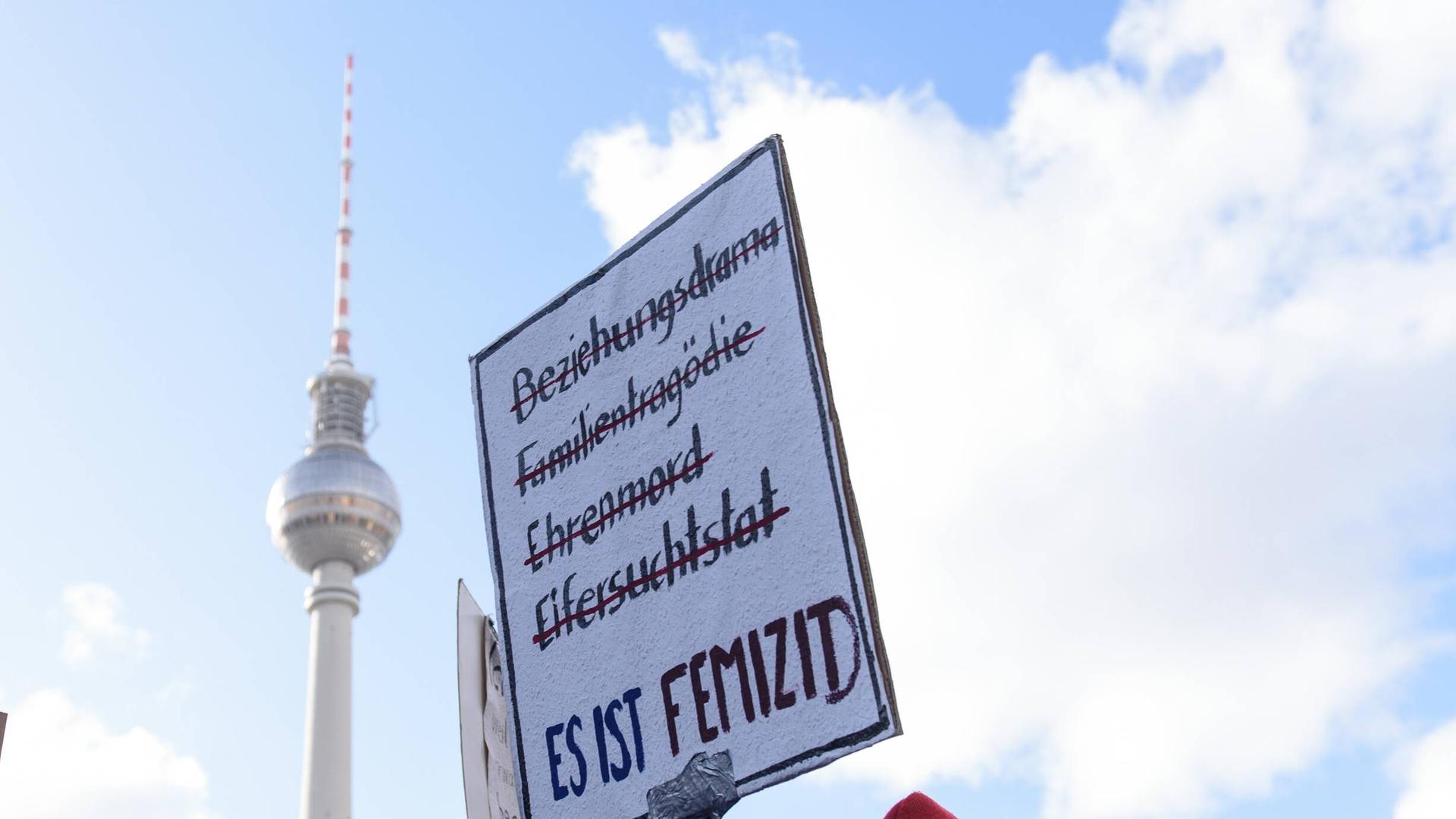 Demonstration am 8. März anlässlich des Internationalen Frauentags in Berlin. Im Bild ist ein Schild mit der Aufschrift Beziehungsdrama, Familientragödie, Ehrenmord, Eifersuchstat - es ist femizid und im Hintergrund der Fernsehturm zu sehen. 