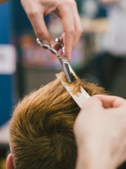 Eine Friseur schneidet einer Person die Haare. 