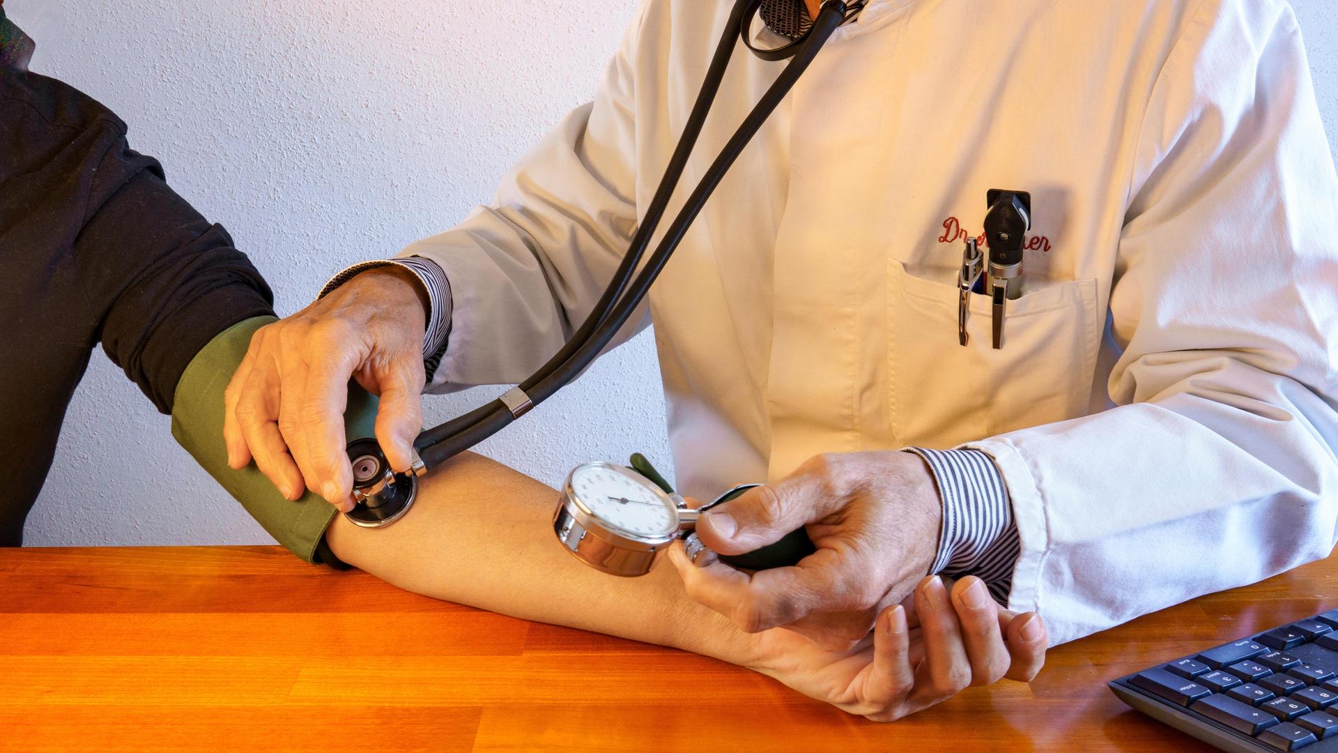 Besuch in der Praxis des Hausarztes. Arzt im Laborkittel misst den Blutdruck eines Patienten. Gesundheitswesen. Nahaufnahme 