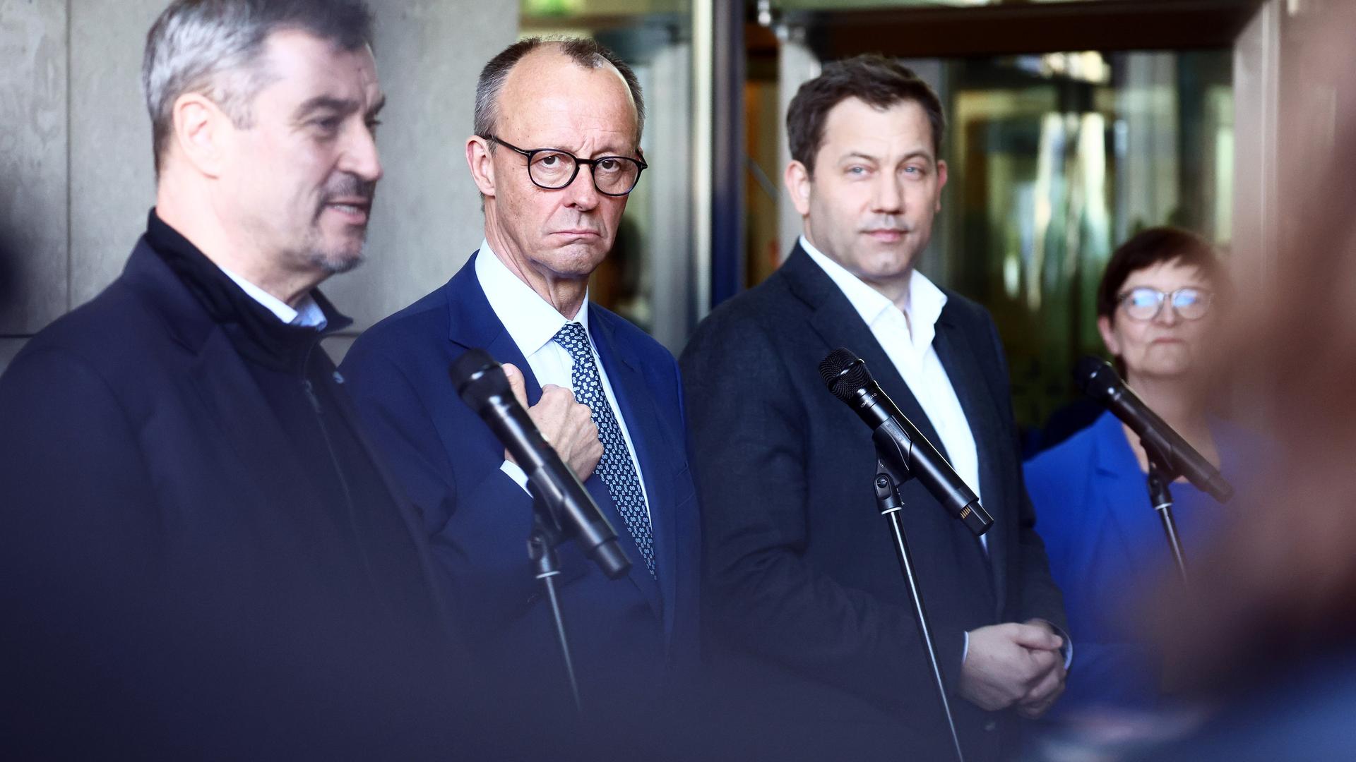 Markus Söder, Friedrich Merz, Lars Klingbeil und Saskia Esken stehen nebeneinander vor Mikrofonen bei einer Pressekonferenz.