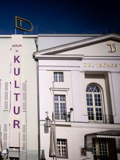 An dem Gebäude des Deutschen Theaters in Berlin, einem neoklassizistischen Bau, ist ein großes Transparent mit der Aufschrift "Kultur" angehängt. Es geht vom Giebel bis zum Boden.