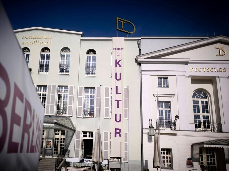An dem Gebäude des Deutschen Theaters in Berlin, einem neoklassizistischen Bau, ist ein großes Transparent mit der Aufschrift "Kultur" angehängt. Es geht vom Giebel bis zum Boden.