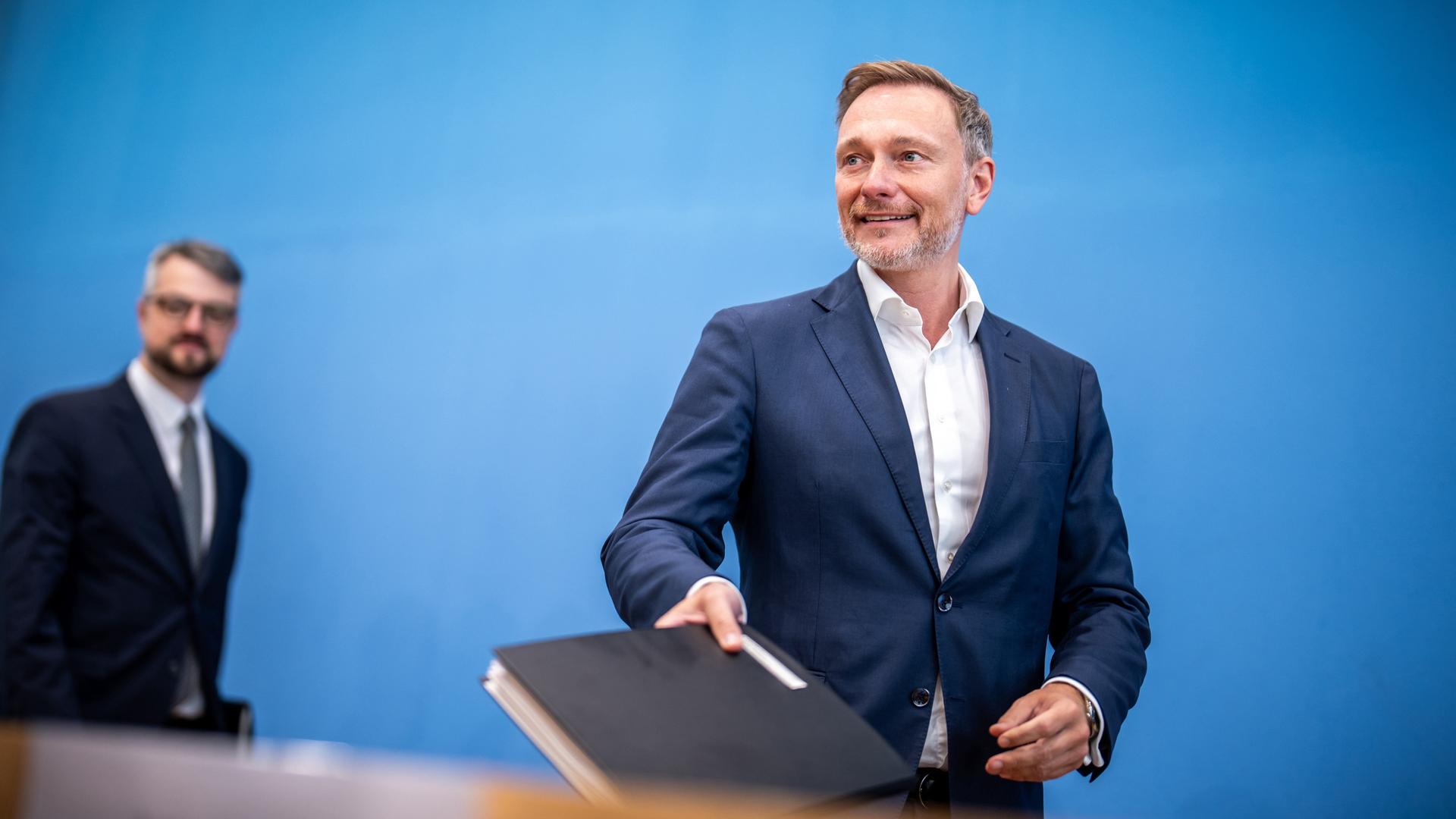 Christian Lindner, Bundesminister der Finanzen, kommt neben Wolf Heinrich Reuter, Staatssekretär im Finanzministerium für den Haushalt, zu einer Pressekonferenz. Er hält eine dicke Mappe in der Hand. Christian Lindner, Bundesminister der Finanzen, kommt neben Wolf Heinrich Reuter, Staatssekretär im Finanzministerium für den Haushalt, zu einer Pressekonferenz. Er hält eine dicke Mappe in der Hand.