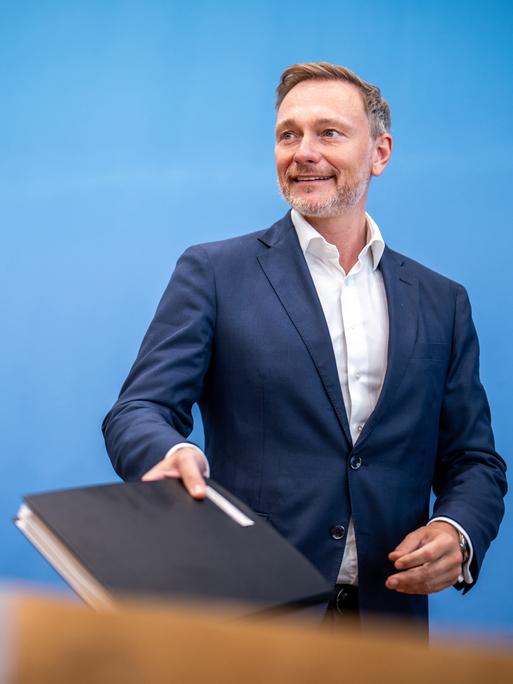 Christian Lindner, Bundesminister der Finanzen, kommt neben Wolf Heinrich Reuter, Staatssekretär im Finanzministerium für den Haushalt, zu einer Pressekonferenz. Er hält eine dicke Mappe in der Hand.