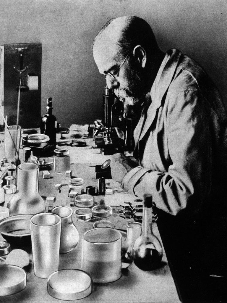 Schwarz-Weiß-Aufnahme: Robert Koch blickt in ein Mikroskop. 