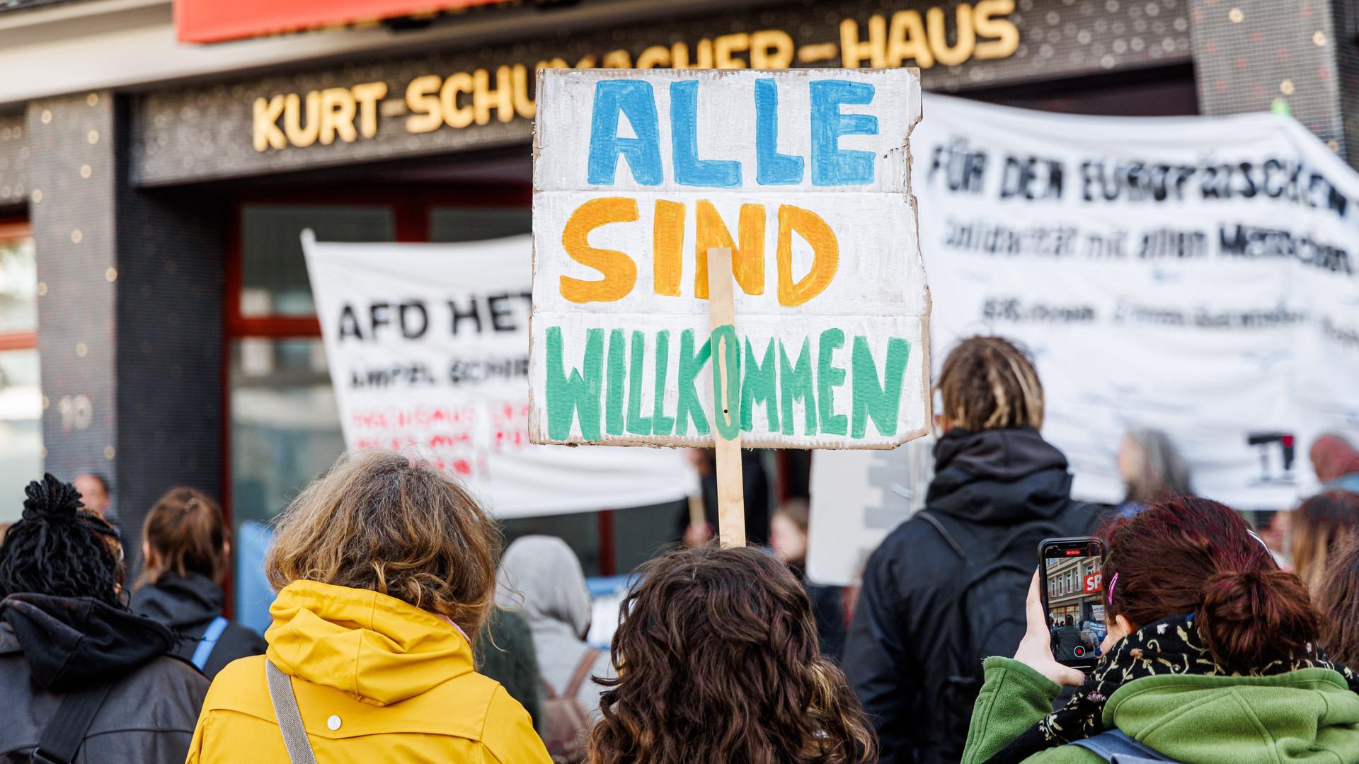 Demonstranten protestieren gegen die FlüchtlingspolitiK: Auf einem Schild steht "Alle sind willkommen"