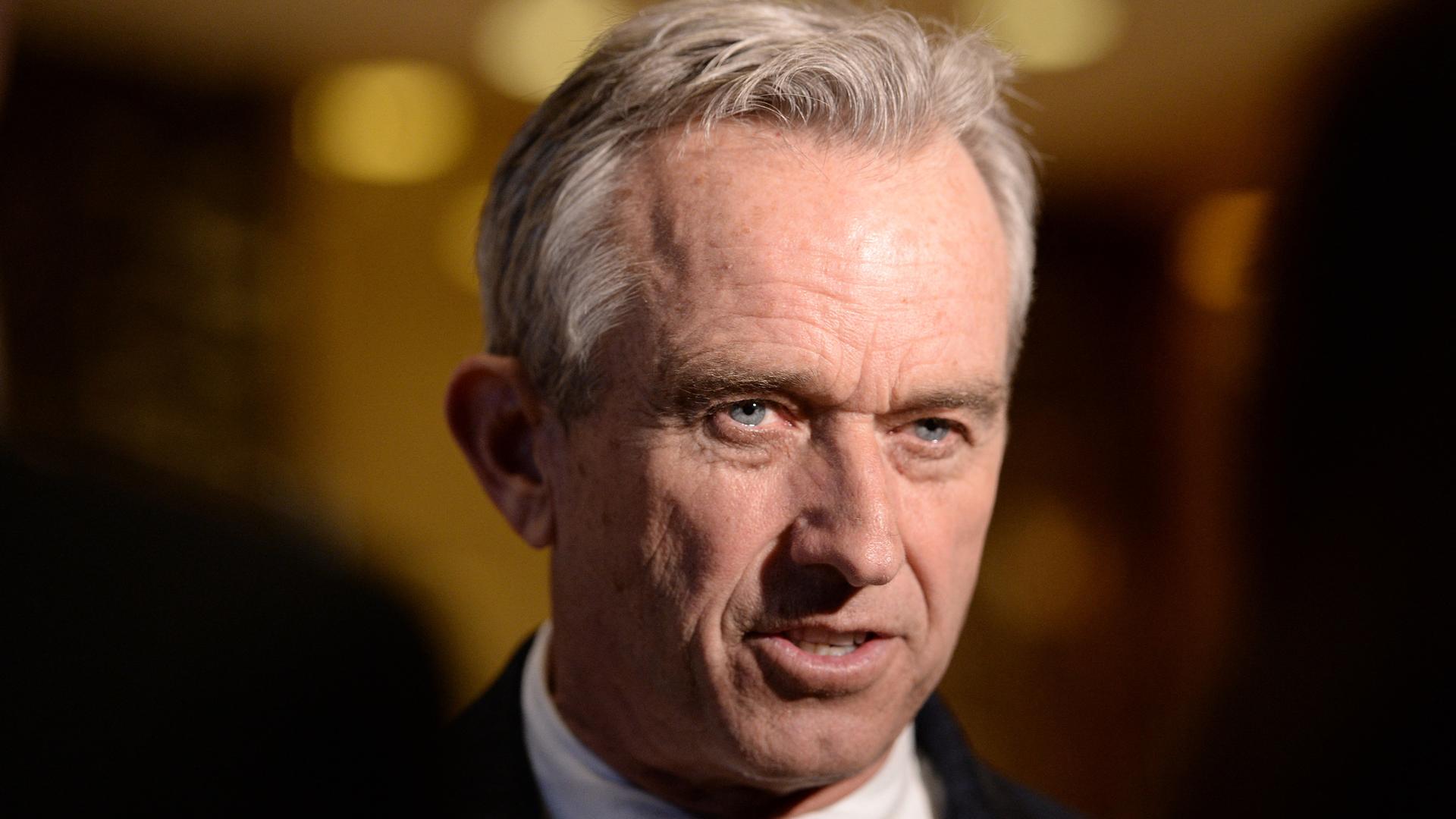 Portraitfoto von Robert F. Kennedy Jr. im Anzug vor dunklem Hintergrund