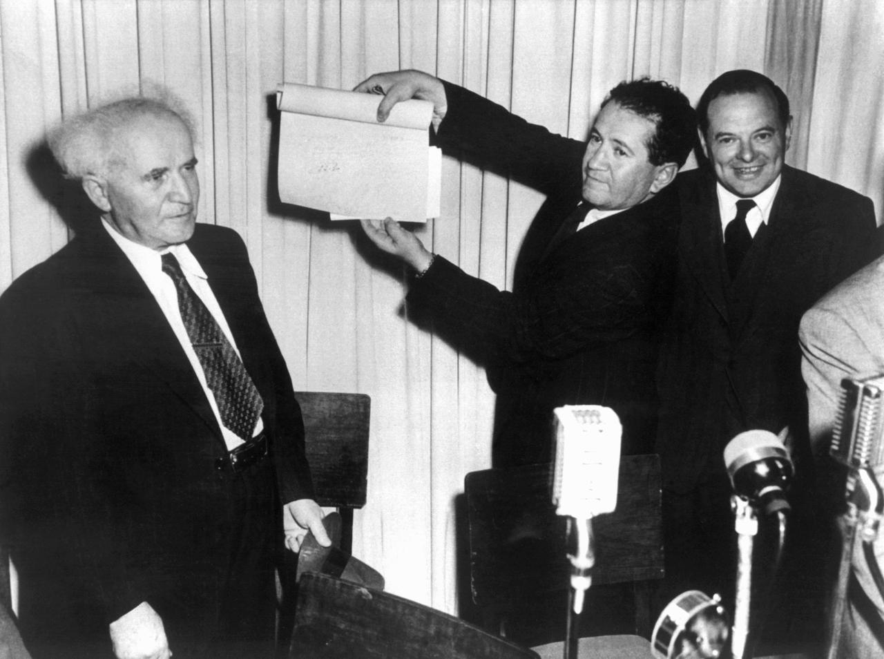 Nach der Unterzeichnung der Proklamationsurkunde am 14. Mai 1948 im Stadtmuseum von Tel Aviv hält eine nicht identifizierte Person das Schriftstück mit den Unterschriften in die Höhe, links David Ben Gurion, der erste Ministerpräsident Israels. In Anwesenheit von mehreren hundert Personen hatten Vertreter aller jüdischer Parteien und der Jewish Agency die "Unabhängigkeits-Deklaration" des neuen jüdischen Staates Israel unterzeichnet.