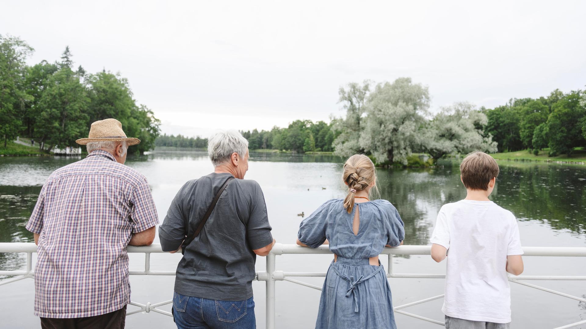 Ältere Frau und Mann gucken mit einem Mädchen und einem Jungen auf einen See.