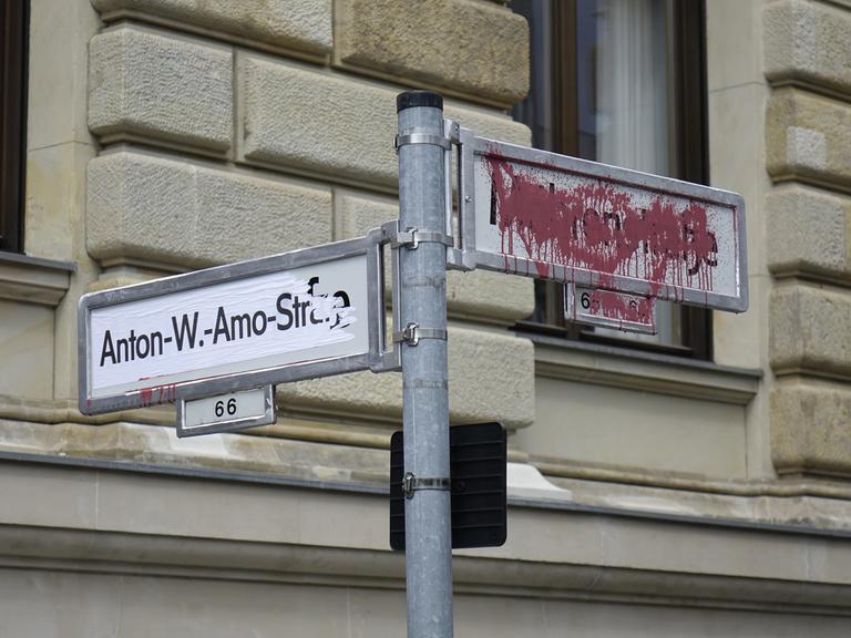 Strassenschild der Anton-Wilhelm-Amo-Straße, daneben ein Strassenschild, was nicht zu erkennen ist weil es besprüht ist