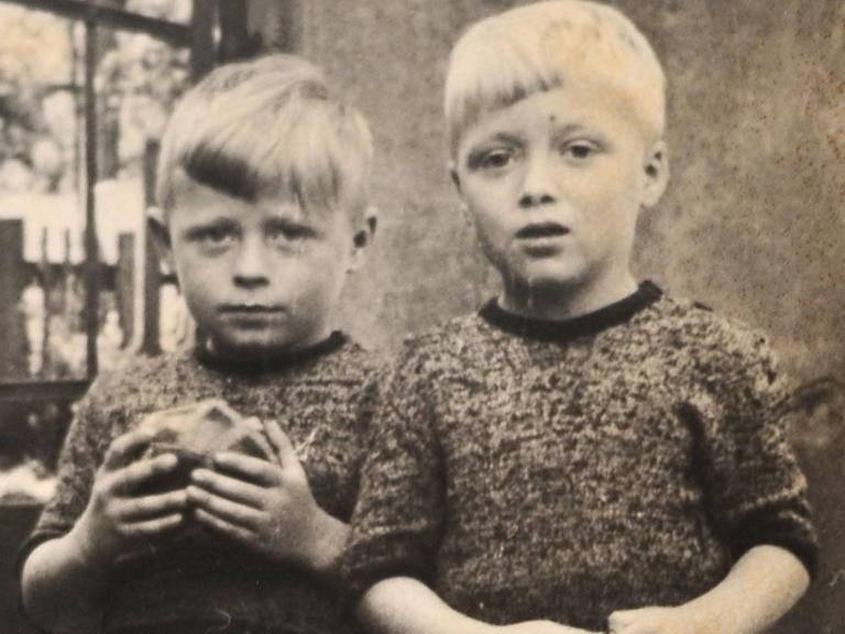 Eine alte Fotografie zweier Kinder. Eines hält einen Ball in der Hand.