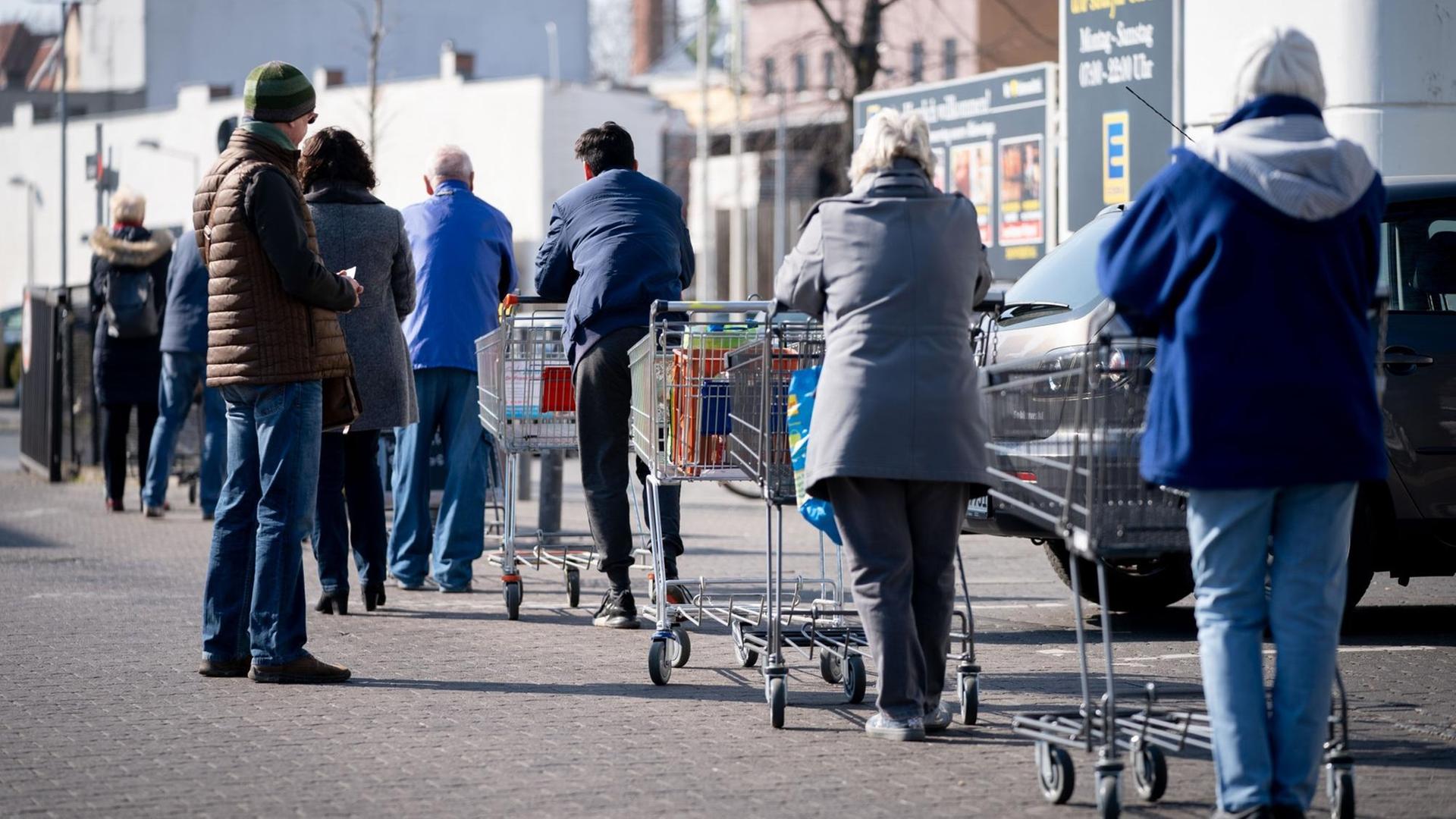 Eine lange Schlange bildet sich vor einem Supermarkt im Stadtteil Reinickendorf. Um die Ausbreitung des Coronavirus zu verlangsamen hat die Bundesregierung das öffentliche Leben weiter erheblich eingeschränkt.
