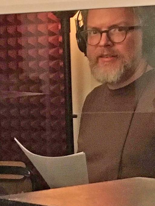 Jonathan Mitchell steht in einem Tonstudio und trägt einen Kopfhörer.