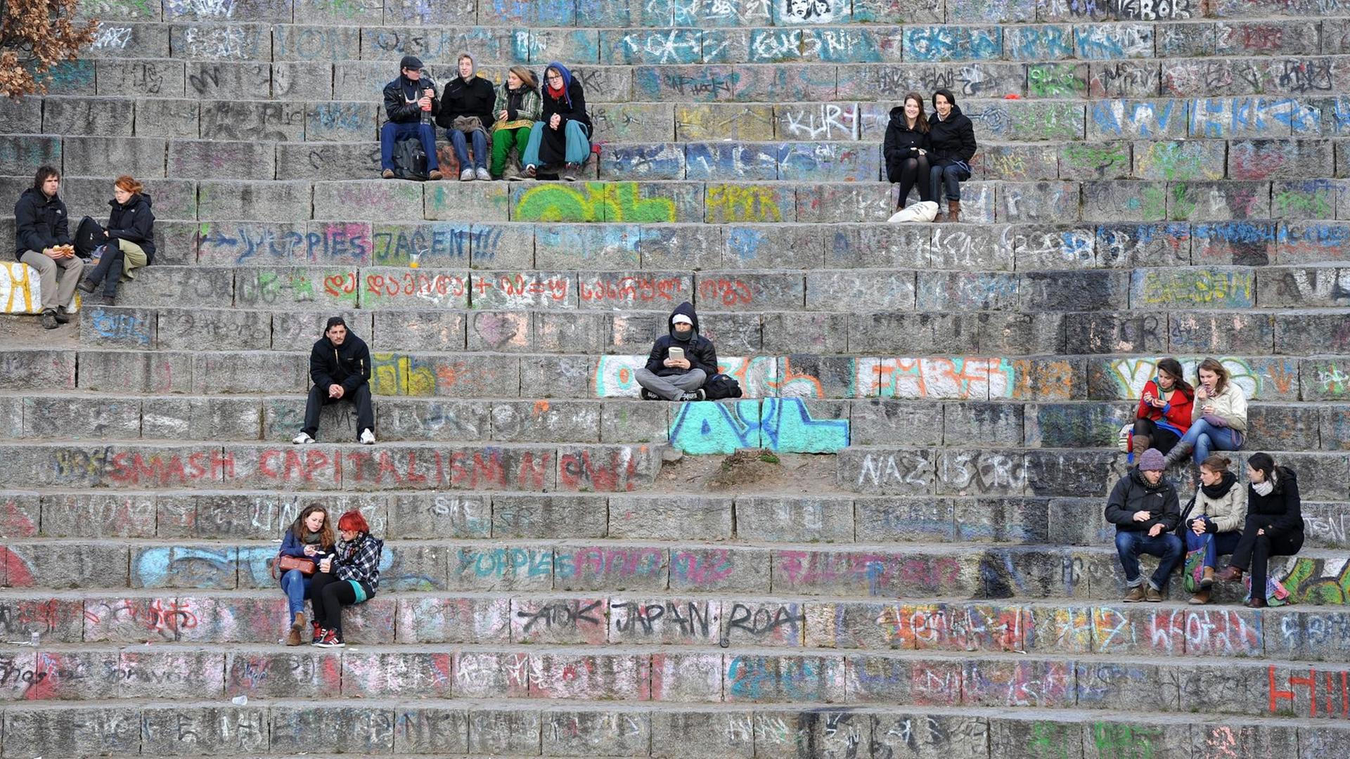 Menschen sitzen auf den Stufen des kleinen Amphitheaters im Mauerpark in Berlin. Der Park im ehemaligen Grenzgebiet zwischen beiden Berliner Stadthälften ist ein beliebter Treffpunkt.