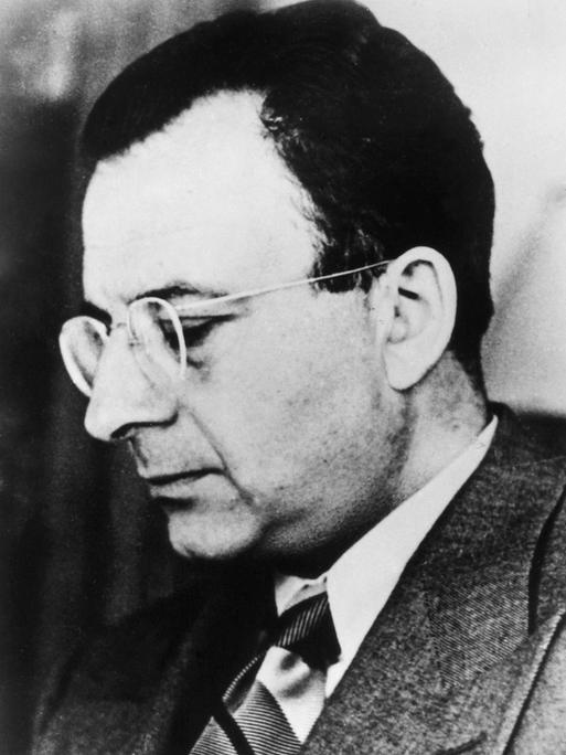 Schwarz-weiße Seitenaufnahme von Erich Fromm mit Brille und im Anzug.