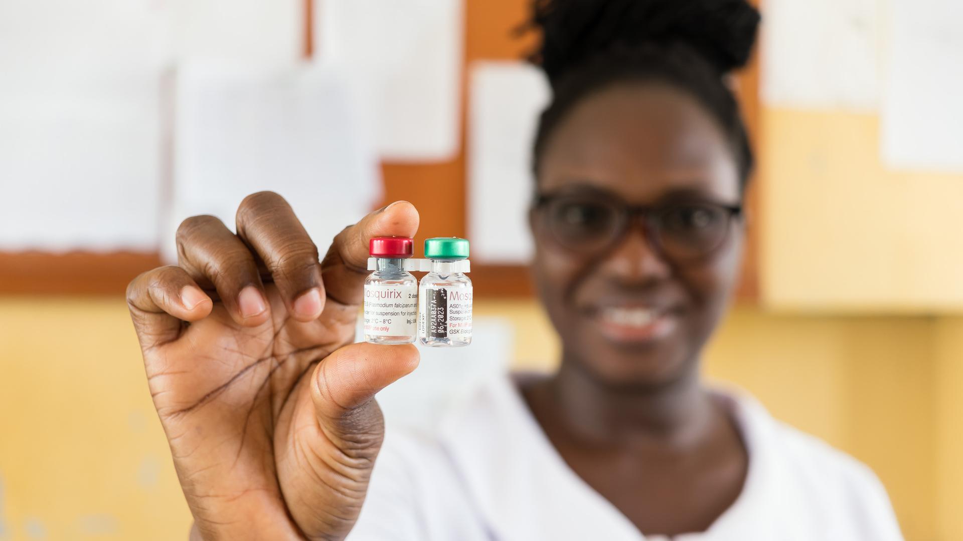 Eine Mitarbeiterin der Poliklinik in Capecoast hält zwei Döschen mit dem Impfstoff Mosquirix in die Kamera