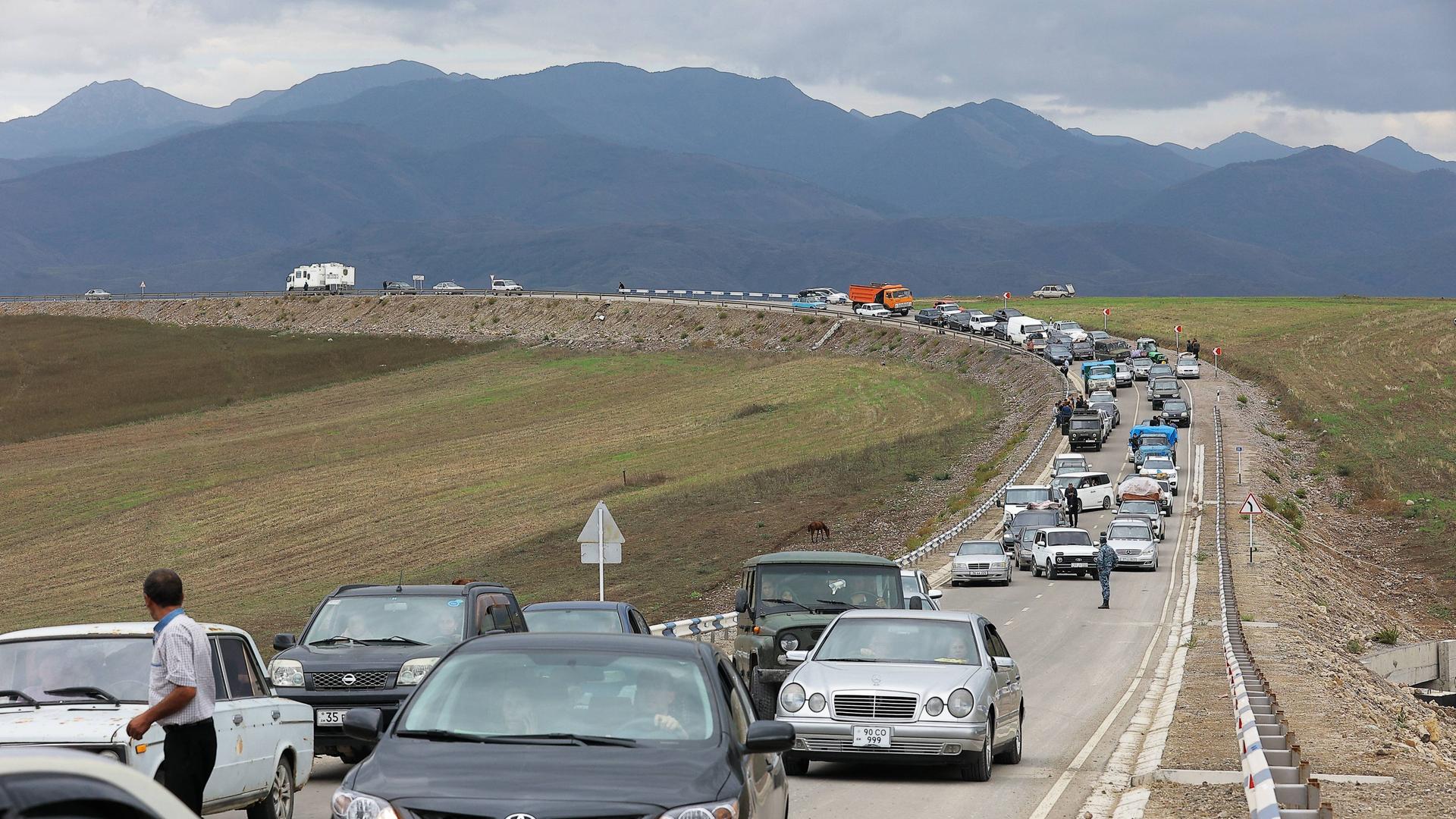 Flüchtende aus Bergkarabach warten in Autos in einer Schlange auf einer Straße auf die Einreise nach Armenien. Im Hintergrund sind Berge des Kaukaus zu sehen. Flüchtende aus Bergkarabach warten in Autos in einer Schlange auf einer Straße auf die Einreise nach Armenien. Im Hintergrund sind Berge des Kaukaus zu sehen.