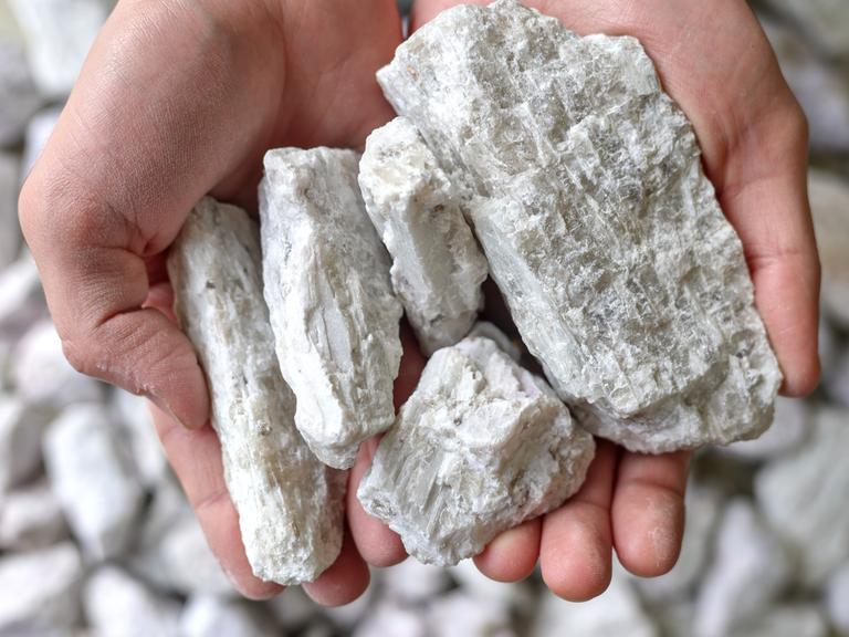 Hände halten ein weißes Gestein, das Lithium enthält(Symbolbild)