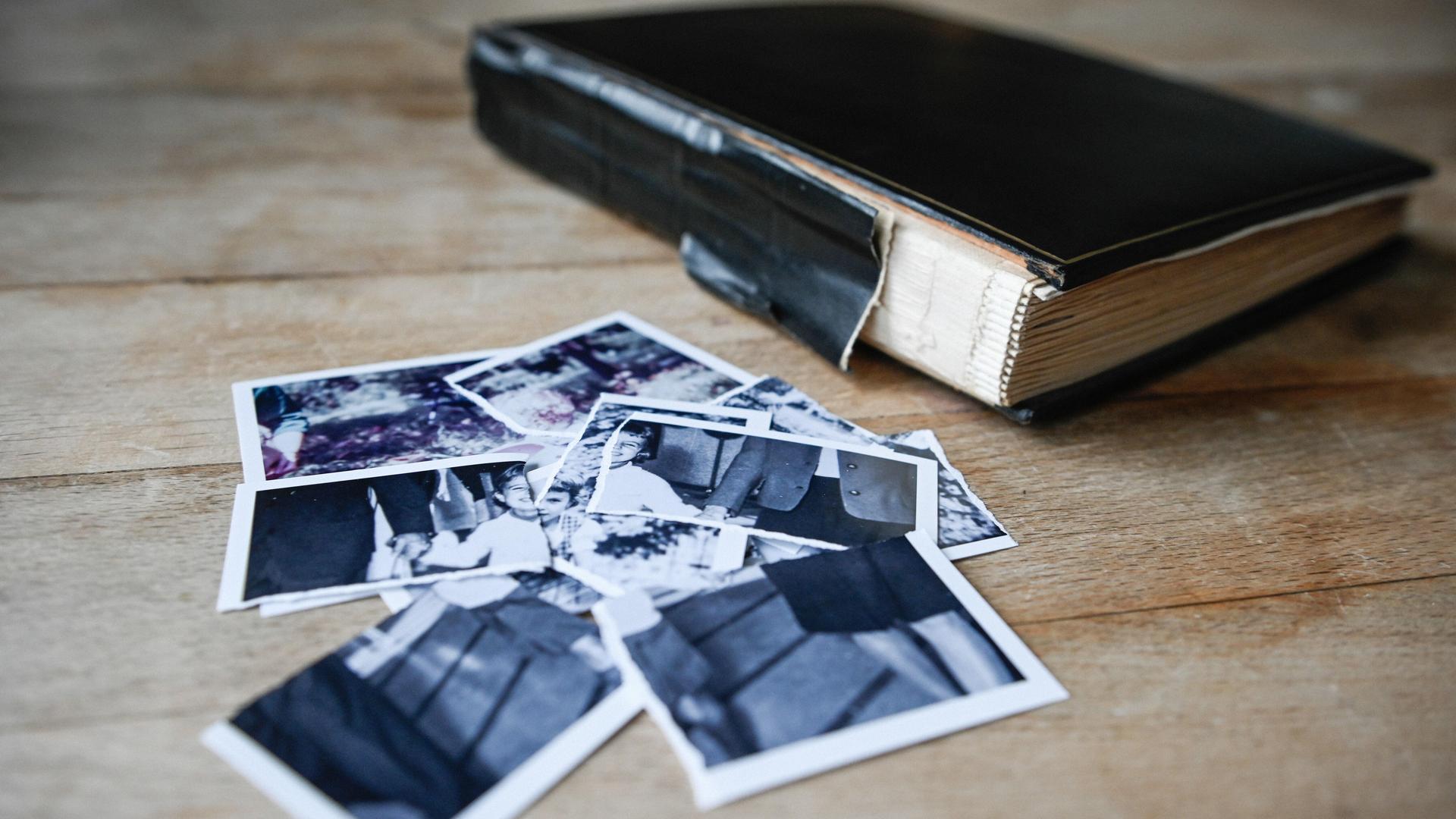 Zerrissene Kinderbilder liegen auf einem kleinen Haufen neben einem Fotoalbum auf einem Tisch am 27. Januar 2022 in Bonn.