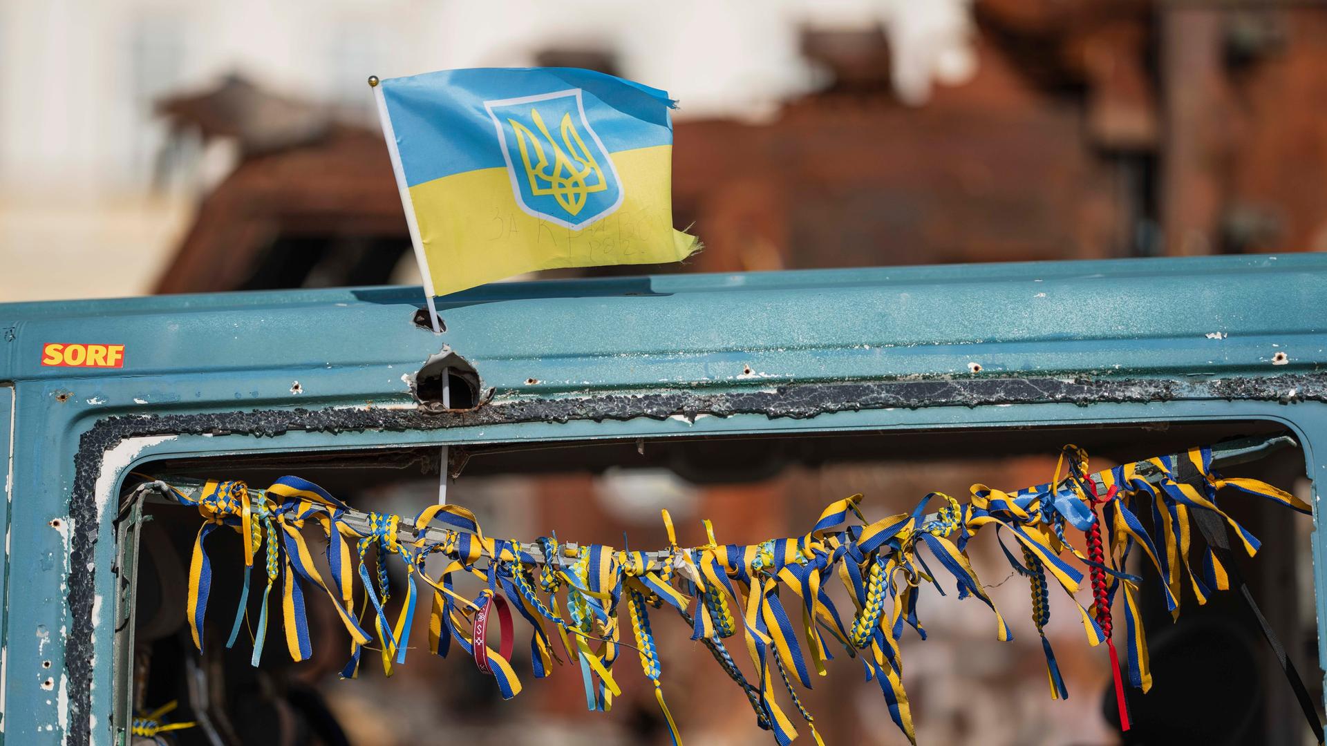 Eine kleine ukrainische Flagge March am einem zerstörten russischen Fahrzeug, das in Kiew im Stadtzentrum ausgestellt steht. 