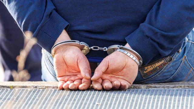 Ein Mann trägt Handschellen nach seiner Festnahme durch die Polizei.