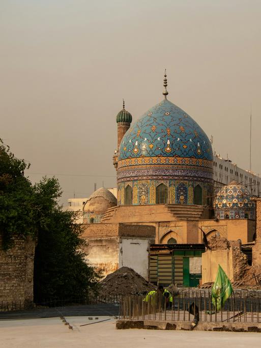 Blick auf eine Moschee mit blauer historischer Kuppel, vor der sich eine Beton-Baustelle eröffnet.
